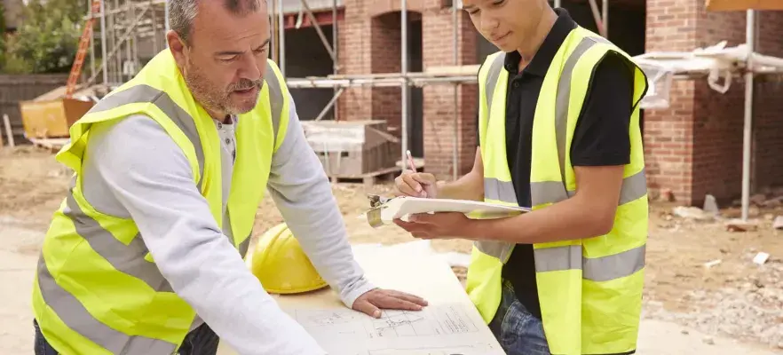 Constructeur sur chantier de construction discuter de travail avec apprenti
